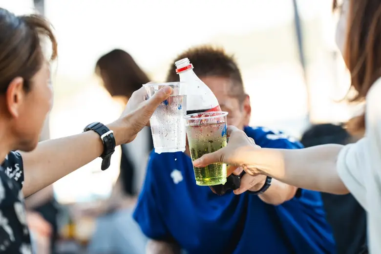 プラスチックカップを合わせて乾杯する人たち。